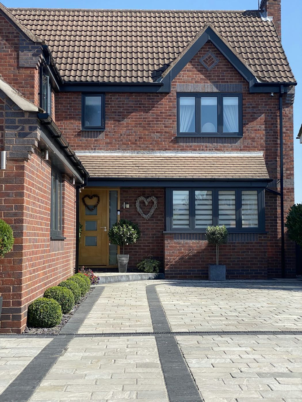 Block paved driveway in front of a brick detached house