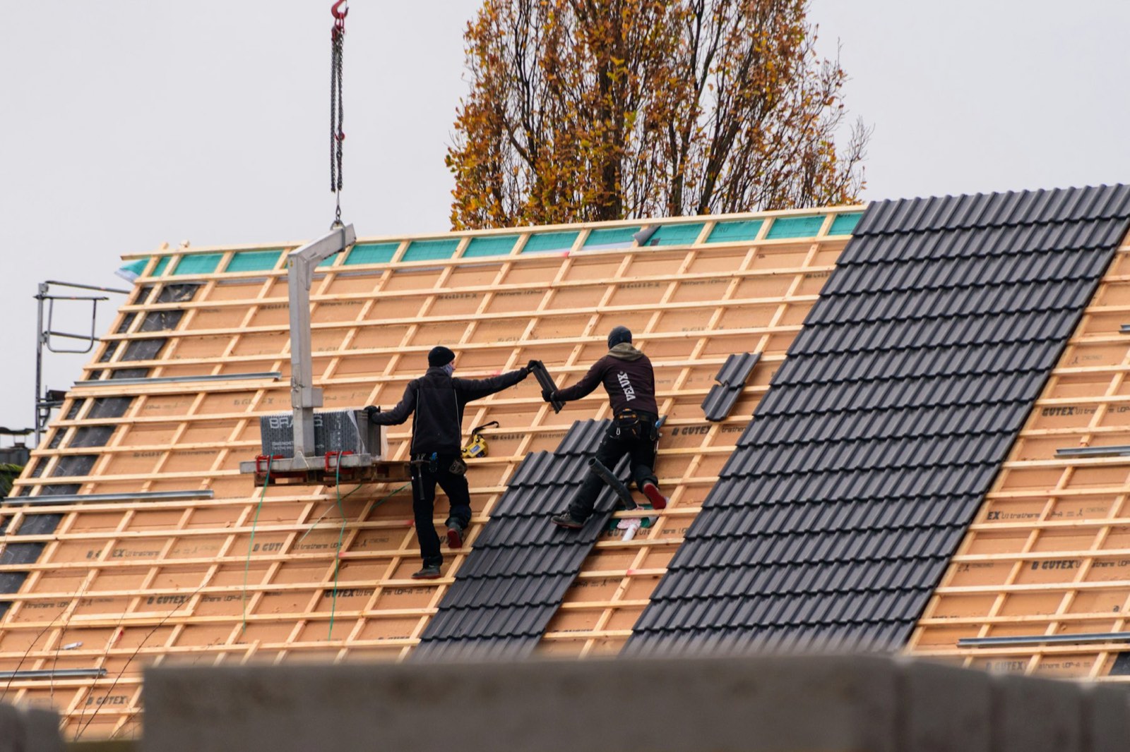 Roofers laying new tiles on a pitched roof